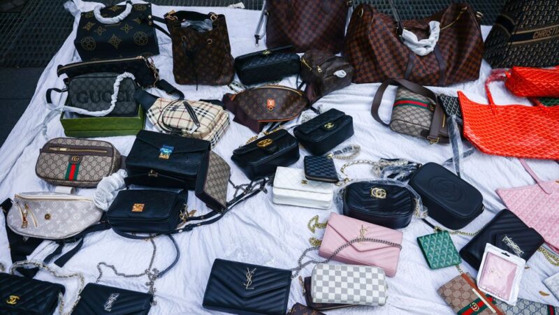 Various purses are scattered on a tabletop covered by a white cloth