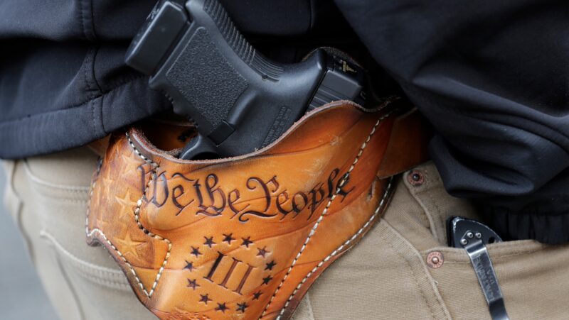 An attendee at a gun rights rally open carries his gun in a holster that reads 